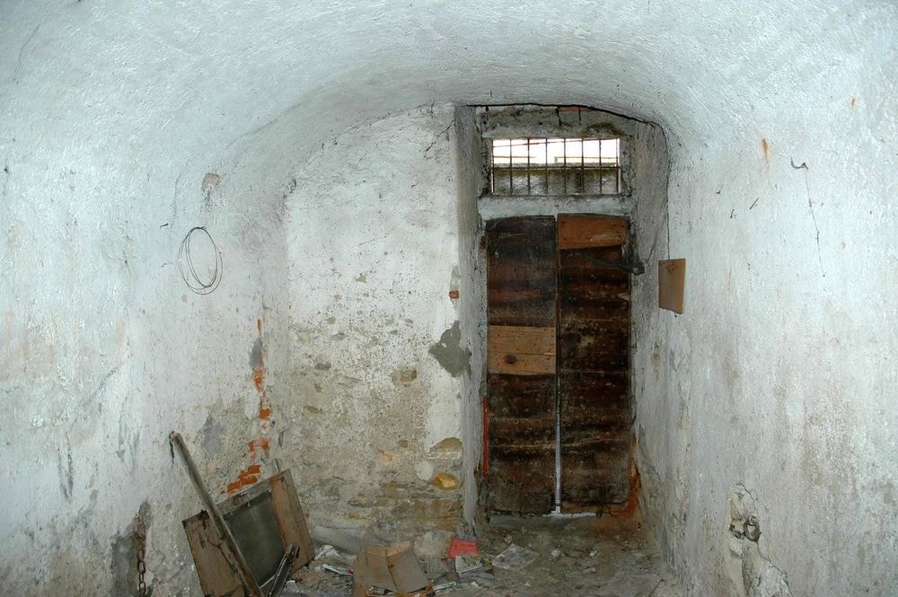 Anni 2000. Portone Chiesa via Gropp. SOTTO L'ALTARE, DIETRO LE SBARRE: IL FASCINO MISTERIOSO DI "UL CATÉLETT" Sotto la chiesa parrocchiale di Stabio, in via "Gropp", si cela una vecchia prigione. Conosciuta in dialetto come "Ul catélett", tra l'Ottocento e il Novecento questa struttura ha ospitato i piccoli trasgressori del paese. In seguito, e fino alla fine degli anni '60, è diventata una cella di rigore per i soldati indisciplinati impegnati nei corsi di ripetizione a Stabio. Come mostra la seconda fotografia, l'antico muro conserva ancora gli anelli a cui venivano assicurati i prigionieri con una catena per impedirne la fuga.